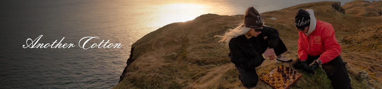 a guy and a girl sitting on the edge of a hill in front of the sea and the sunset