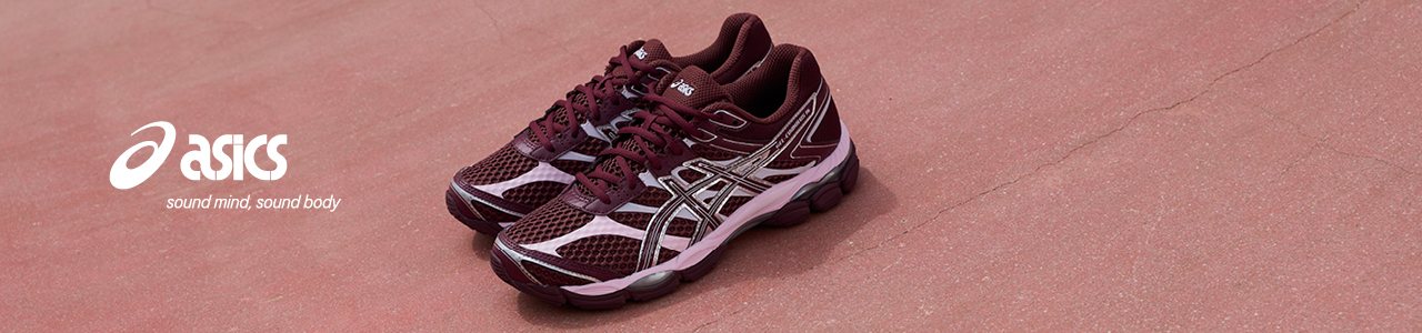 Image of pair of pink and metallic grey asics sneakers on pink concrete underground