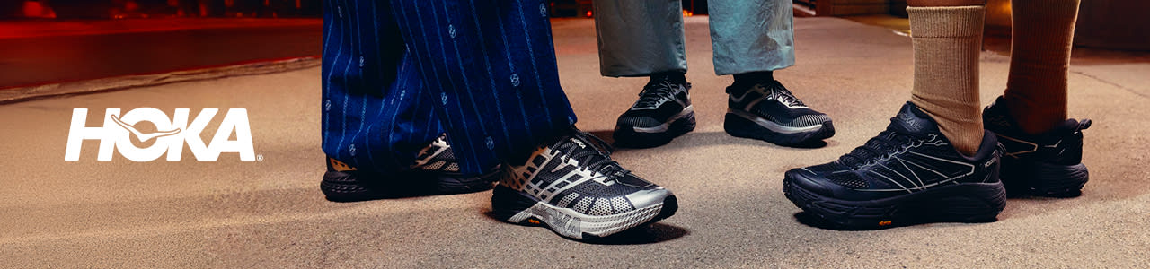 A series of lifestyle and product photographs for the Hoka StealthTech Collection. The images feature diverse models wearing technical black and silver Hoka sneakers while navigating urban environments at night. Highlights include close-ups of reflective mesh detailing, thick cushioned midsoles with integrated logos, and models running across city crosswalks in high-fashion streetwear, including lime green ruched skirts and textured trousers.