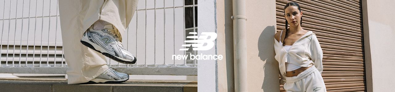 Person sitting on a concrete ledge outdoors, wearing light-colored pants and tying the laces of a silver New Balance sneaker, with the New Balance logo and text displayed on the left side.