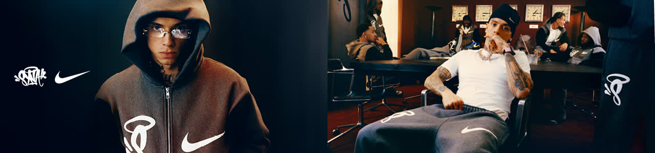 A panoramic promotional banner for a Nike collaboration featuring British rapper Central Cee. The left side is a portrait of Central Cee wearing a dark grey Nike zip-up hoodie with the hood up and rimless glasses, positioned next to a white Nike swoosh and a "Syna" graffiti-style logo. The right side shows a wide shot of Central Cee sitting at a conference table in a moody, corporate setting, surrounded by other men. He is wearing a white t-shirt, grey Nike sweatpants, a black beanie, and silver jewelry. The Nike swoosh is prominently displayed on the apparel and the wall.