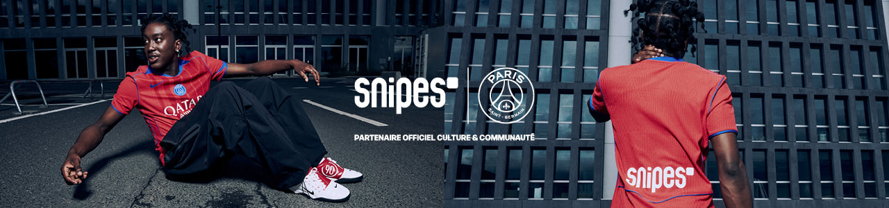 Model standing in front of urban building wearing a red football jersey from the PSG 3rd kit
