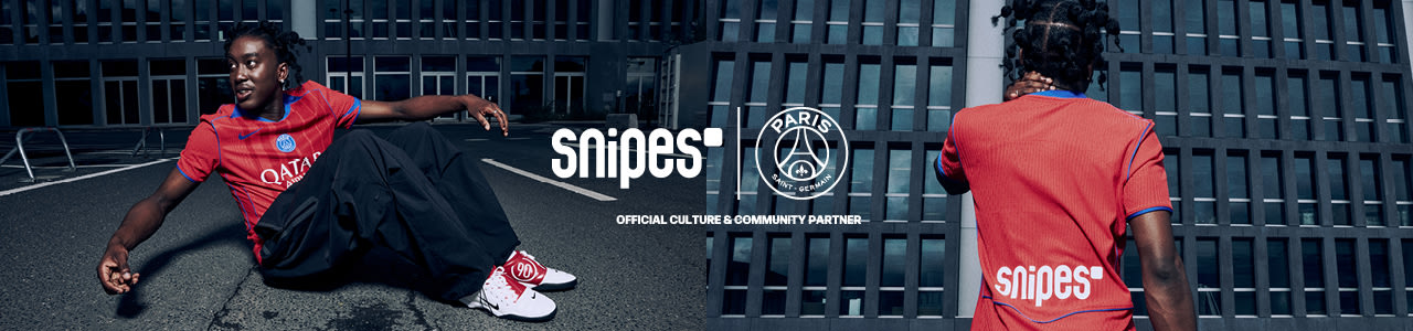Model standing in front of urban building wearing a red football jersey from the PSG 3rd kit