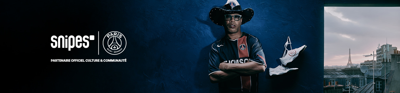 A man wearing a cowboy hat, sunglasses, and a Paris Saint-Germain (PSG) football jersey poses confidently with arms crossed. He is also wearing metallic gold pants with the word "Snipes" printed on them and stands against a dark blue textured background. A pair of white football boots with red accents hangs in the air beside him. The Snipes and PSG logos are displayed in the top right corner with the text “Partenaire Officiel Culture & Communauté.”