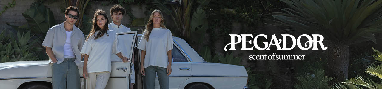 Four models wearing light, casual summer outfits pose in front of lush greenery under the branding "PEGADOR – scent of summer." The scene evokes a relaxed, stylish summer vibe with a natural tropical backdrop.