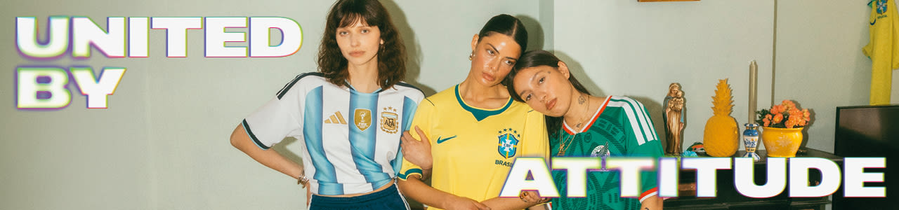 A promotional banner featuring five young individuals hanging out during a casual outdoor gathering in a backyard or patio setting. One person sits near a small charcoal grill with food cooking on it, while the others are seated around a patio table with food and drinks. They are all wearing different national football team jerseys, including France, Italy, Brazil, and Argentina. Large, stylized text overlays the image, with "UNITED BY" in the top-left corner and "ATTITUDE" across the bottom right, both featuring a bold white font with a soft neon glow.