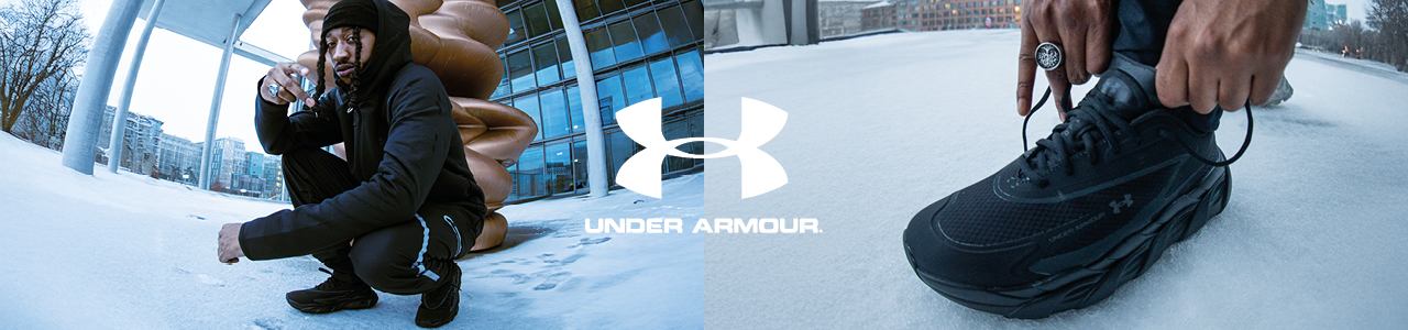 A person dressed in a black Under Armour "Unstoppable" hooded jacket, beanie, and matching joggers crouches in a snowy outdoor setting. The scene features a futuristic architectural backdrop with a large, bronze-colored abstract sculpture. One view highlights a close-up of the person tying the laces of a black Under Armour athletic shoe against the snow. The Under Armour logo is prominently displayed.