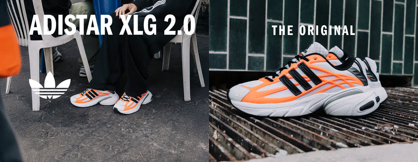 An advertisement image for the Adidas Adistar running shoes. The text "ADISTAR" is written in large white letters at the top. Below the text and the Adidas Trefoil logo, two pairs of the shoes are visible. One pair, with an orange and black color scheme, is hanging in the center. Another two pairs, one silver and black and one white and black, are sitting side-by-side on a ledge in the foreground. The background is a dark window with green metal grating.