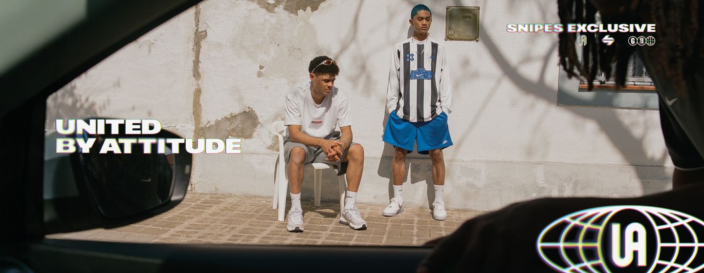 Top-down shot of a pair of white Nike Air Force 1 sneakers resting on a sunlit, textured concrete ground marked with white lines. The shoes feature a crinkled leather upper, metallic silver Swooshes, and translucent icy blue outsoles. One shoe lies on its side while the other stands upright. The top-left corner features the text "UNITED BY ATTITUDE" in a bold, outlined font, and the right side includes a vertical "SNIPES EXCLUSIVE" logo.