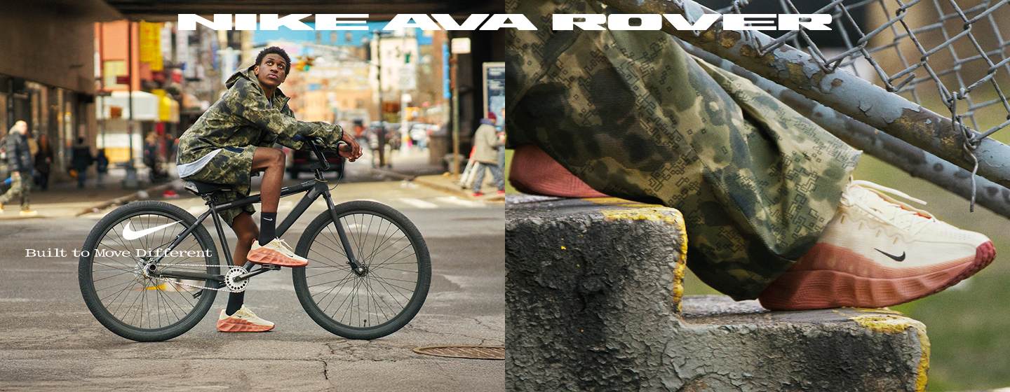 A young man wearing a camouflage jacket and shorts sits on a black bicycle in an urban setting. He is wearing Nike AVA Rover sneakers, which are prominently featured in the image. The shoes are light beige with a bold, thick coral-orange sole. Text on the image reads "NIKE AVA ROVER" at the top and "Built to Move Different" near the shoes, emphasizing the footwear's unique design and functionality.