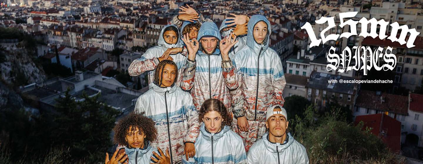 group of people wearing the new 125mm collection of light blue tracksuit with the print of Marseille city over it. In the photo background there is the landscape of Marseille, France.
