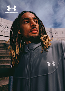 Model sitting on stadium tribune wearing under armour tech utility tracksuit