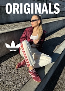 blonde girl wearing adidas originals pink and red sneakers, white adidas pants with red stripes and a red jackets over a white tanktop. 