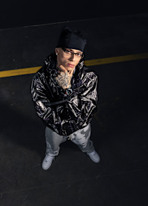 G-Shock Watches presented by Central Cee: He is wearing a leather jacket, grey sweatpants and a black G-Shock watch. He has a black bandana on his head and glasses.