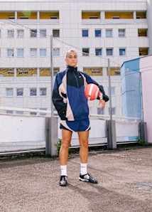 Girl  holding a football while wearing nike sportswear and nike t90 shoes