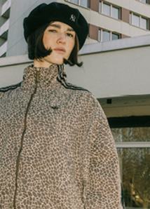 Women wearing track jacket with animal print and a black cap
