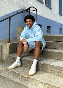 Guy sitting in the stairs wearing a hoodie and pants from adidas and adidas shoes