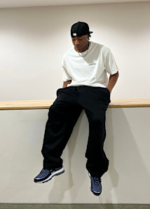 Guy sitting with a oversize white tshirt and baggy panta and a black cap