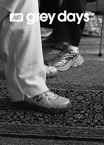 A black and white lifestyle photograph for New Balance's "Grey Days" campaign. The image features two people lounging on a couch; one person is wearing grey sweatpants and a pair of New Balance sneakers with their feet propped up on a wooden coffee table next to a chess set. The text "NB grey days" is overlaid in white on the left side of the frame