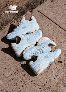 New Balance Sneakers light blue and white at the center of the image,laying on the street 
