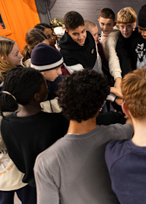 group of teenagers in the snipes hiphop basement standing together and throwing up hands