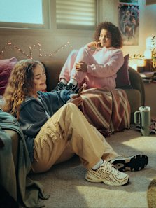 Girls sitting in the sofa with New Balance apparel and sneakers