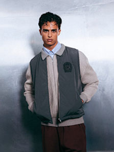 Model wearing autumn streetwear clothing and shoes, while standing in a silver futuristic setting.