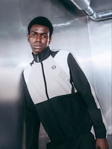 Model wearing autumn streetwear clothing and shoes, while standing in a silver futuristic setting.