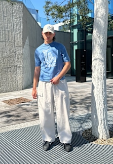 Man wearing a blue t-shirt and a beige cap.