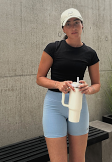 Female model wearing running clothes: blue running shorts and black t-shirt with big sunglasses