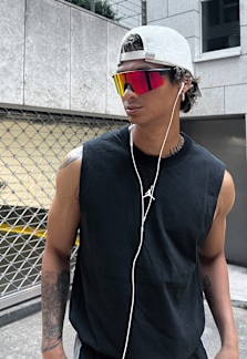 Male model wearing black outfit in running style aesthetics: black running shoes, shorts and tanktop with colorful sunglasses.
