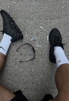 Male model wearing black outfit in running style aesthetics: black running shoes, shorts and tanktop with colorful sunglasses.