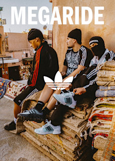 Three people sitting on a stack of carpets wearing the adidas megaride sneaker