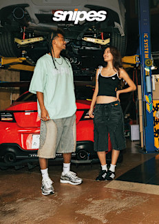 Male and Female standing in front of a red car wearing shorts, snaker and T-Shirts/Tops, from SNIPES