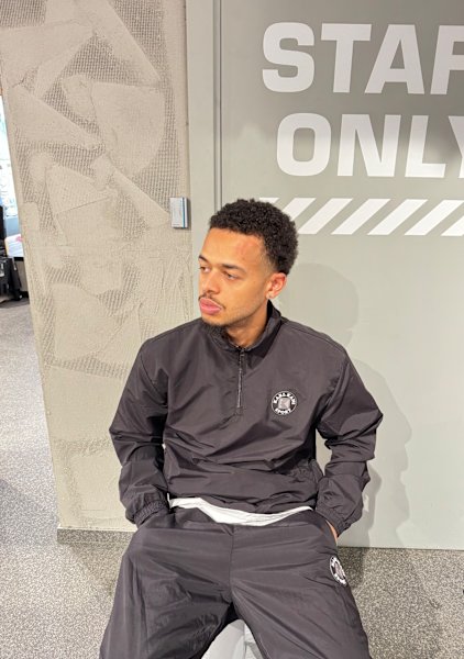 Guy sit down wearing a black tracksuit in a snipes wardrobe 