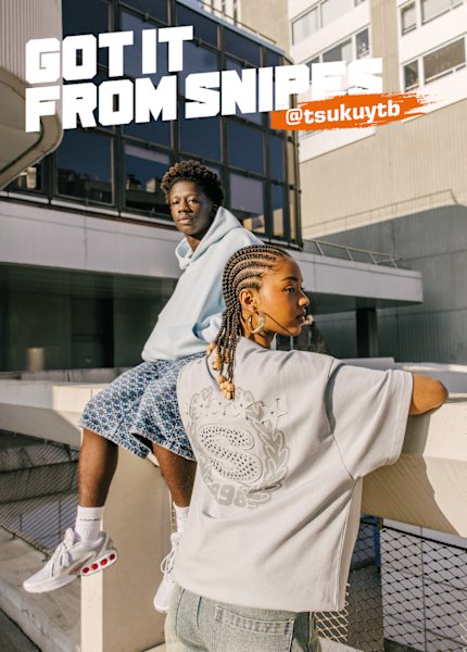 French artist Tsuku and other woman standing in front of city buildings wearing streetwear clothing