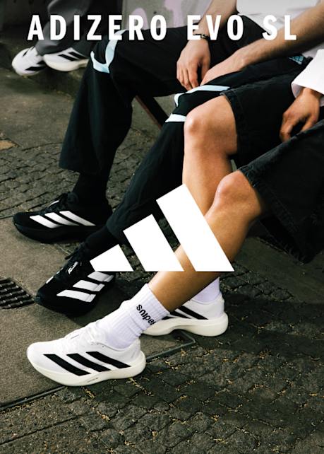 Image of male legs wearing black and white adidas adizero sneakers on concrete floor