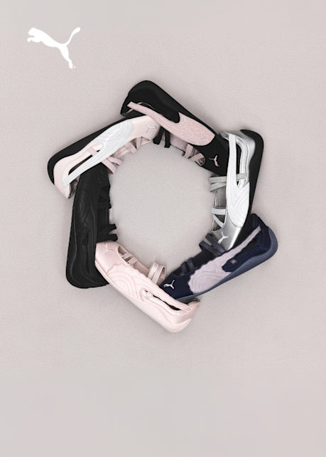 A collection of PUMA ballet-inspired flats in black, metallic silver, soft pink, and navy blue, showcasing their slim profile, crisscross elastic straps, and OrthoLite insoles against a neutral grey background.
