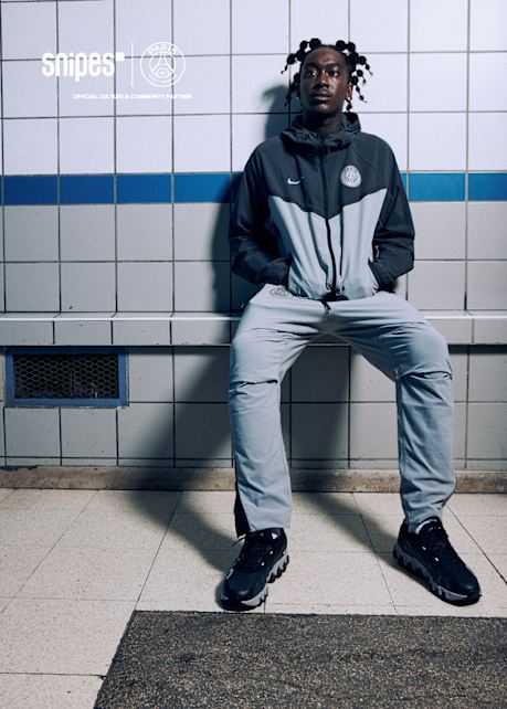 Model wearing blue and grey Nike x PSG tracksuit with dark blue Air Max Dn8 shoes from the PSG Paname collection