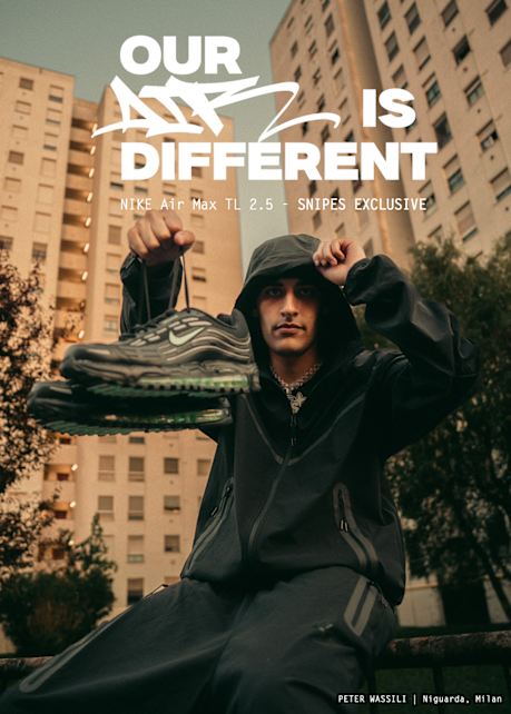 A young man in a black hooded tracksuit sits outdoors in front of tall apartment buildings, holding up a pair of black Nike Air Max TL 2.5 sneakers with green soles. The ad features bold white text reading “OUR AIR IS DIFFERENT” along with “NIKE Air Max TL 2.5 – SNIPES EXCLUSIVE.” At the bottom right