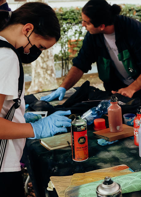 image of young kid standing at table with graffiti materials during snipes school project