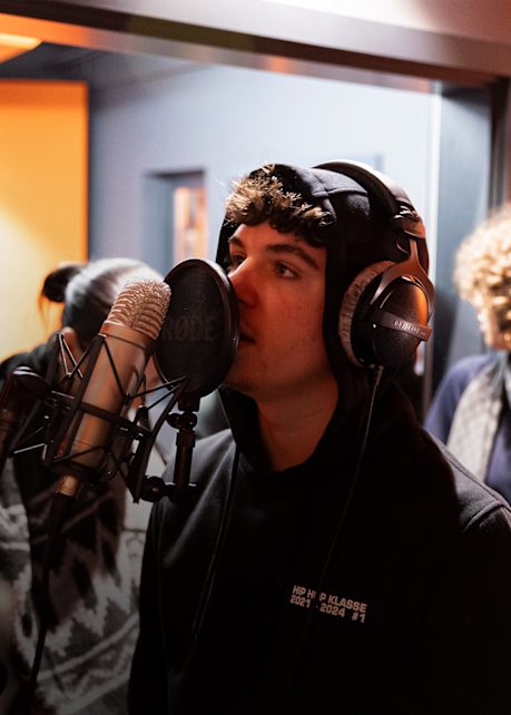 image of artist standing in front of recording mic in snipes hiphop basement