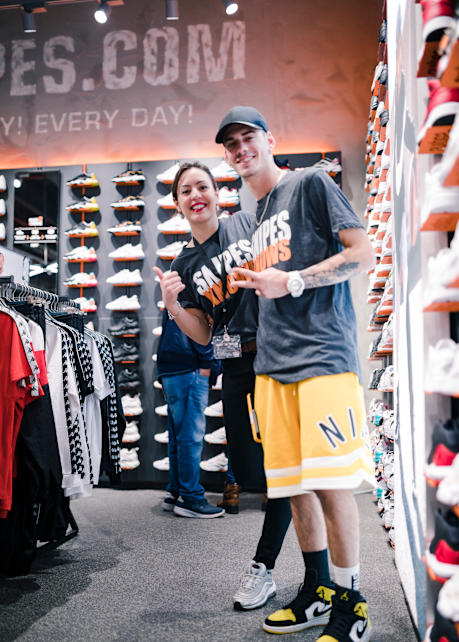 Two employees standing in a SNIPES store in front of a shoe display. 