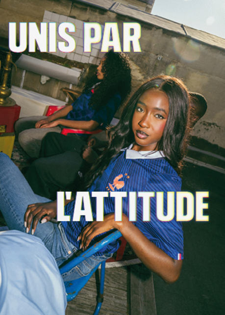 Wide banner featuring three smiling young adults on an urban rooftop, dressed in Nike France soccer apparel. Overlaid on the left and right in large, bold white text with a subtle yellow glow is the French phrase "UNIS PAR L'ATTITUDE". On the left, a man sits in a light-colored jacket with black and red accents. In the center and right, two women sit together wearing blue patterned France national team jerseys with the FFF rooster crest.