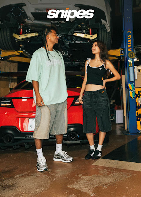 Male and Female standing in front of a red car wearing shorts, snaker and T-Shirts/Tops, from SNIPES