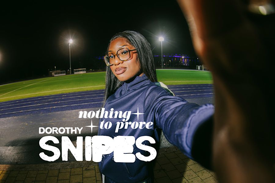 Gemini ha detto A woman with long dark hair and glasses poses for a selfie at a sports stadium at night. She's wearing a blue tracksuit and looking confidently at the camera. Overlaid on the image is the text "nothing to prove," the name "DOROTHY," and the "SNIPES" logo in bold letters. In the background, there's a running track and a lit-up field under stadium lights.